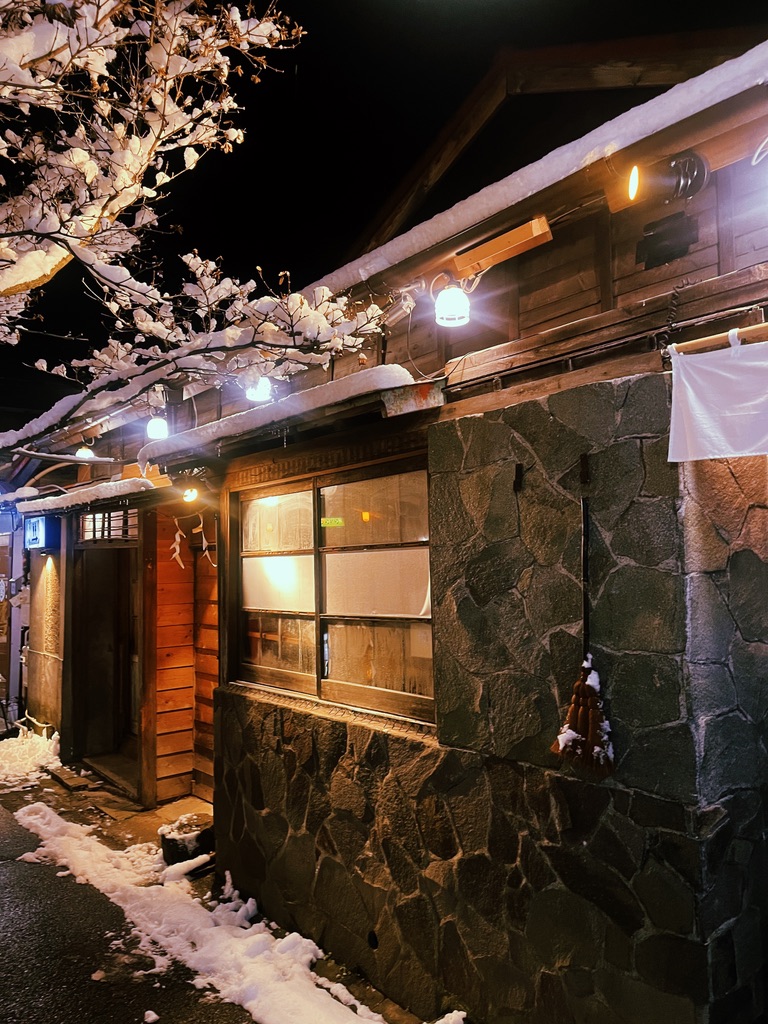 雪の夜に暖かな灯りがともる中華蕎麦よるのふじの外観
