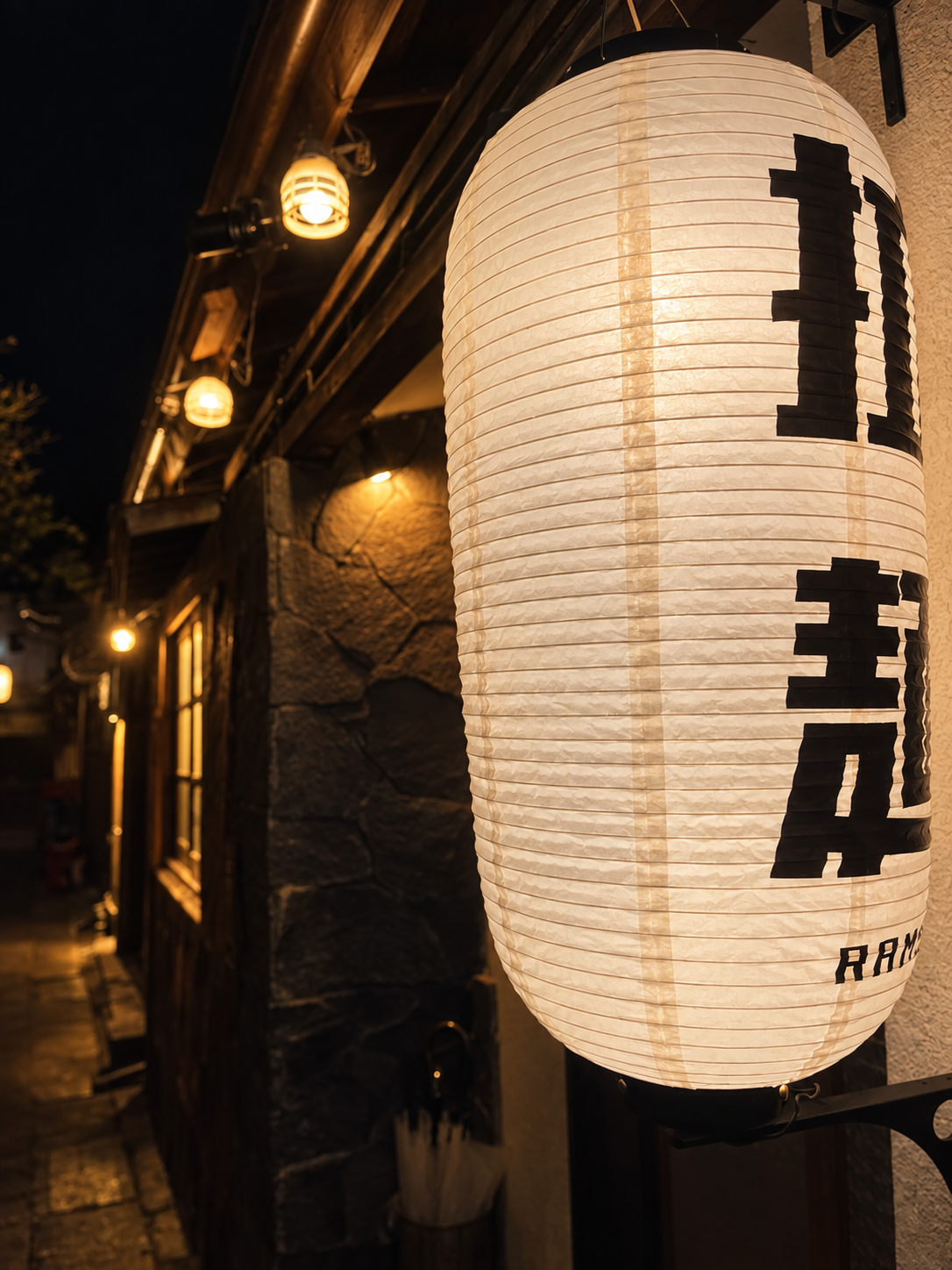 夜の路地を暖かく照らす中華蕎麦よるのふじの白い提灯
